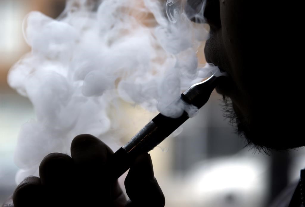 A man smokes an electronic cigarette in Chicago on April 23, 2014. A Quebec Superior Court judge says the province is within its rights to legislate on vaping but has declared certain sections of the law forbidding the demonstration of vaping products inside shops or specialized clinics invalid.