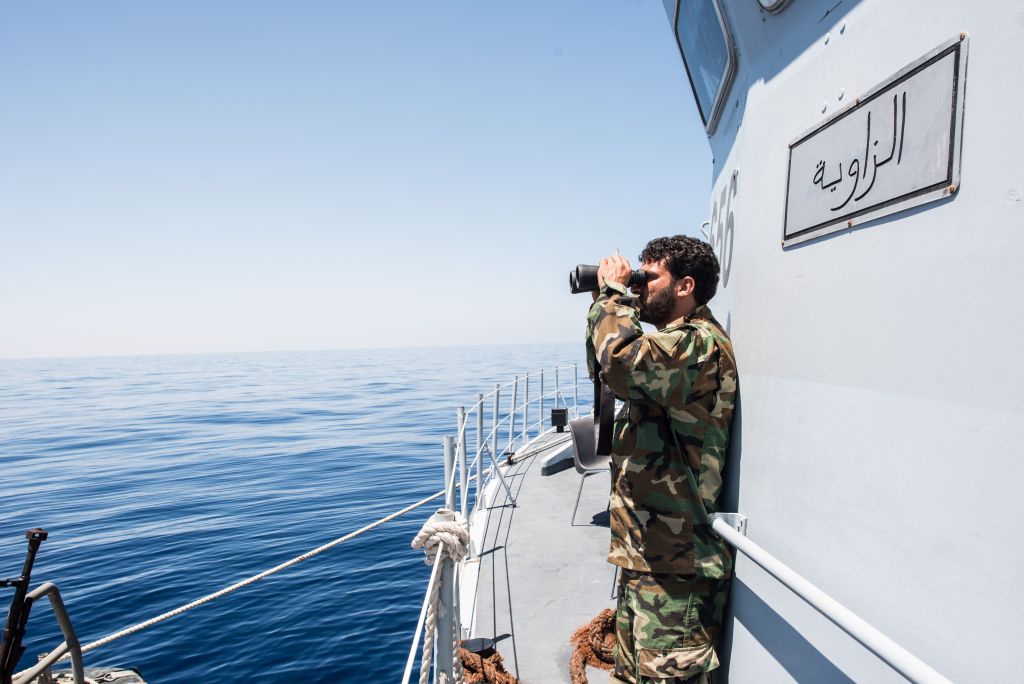 A Libyan coastguard uses binoculars as he patrols the area at sea between Sabratha and Zawiyah on July 28, 2017.