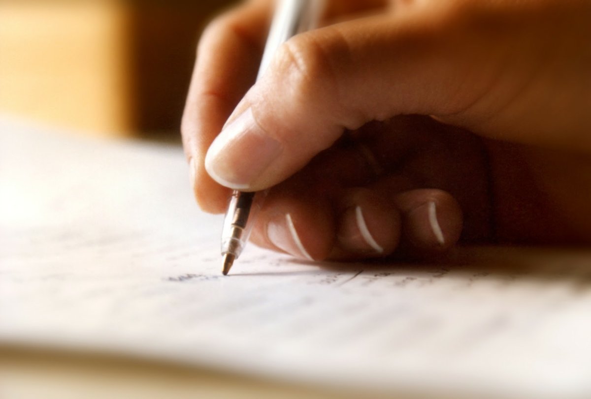 File: A person writing on a piece of paper.