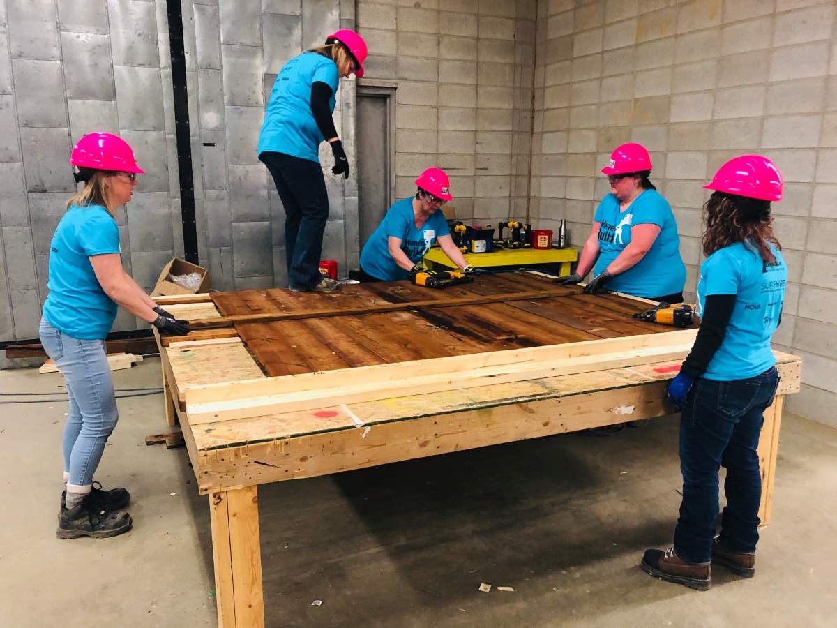 A group builds a section of fencing at the Habitat for Humanity Edmonton Women Build.