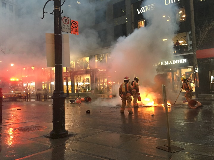 Firefighters  put out a fire on Ste-Catherine Street as May Day protests heat up. Wednesday, May 1, 2019.