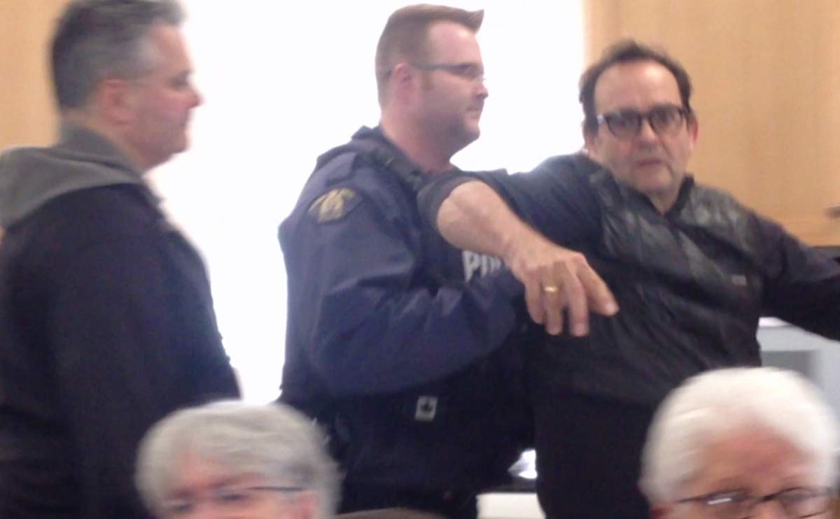 John Perkins being forced out from the room. 