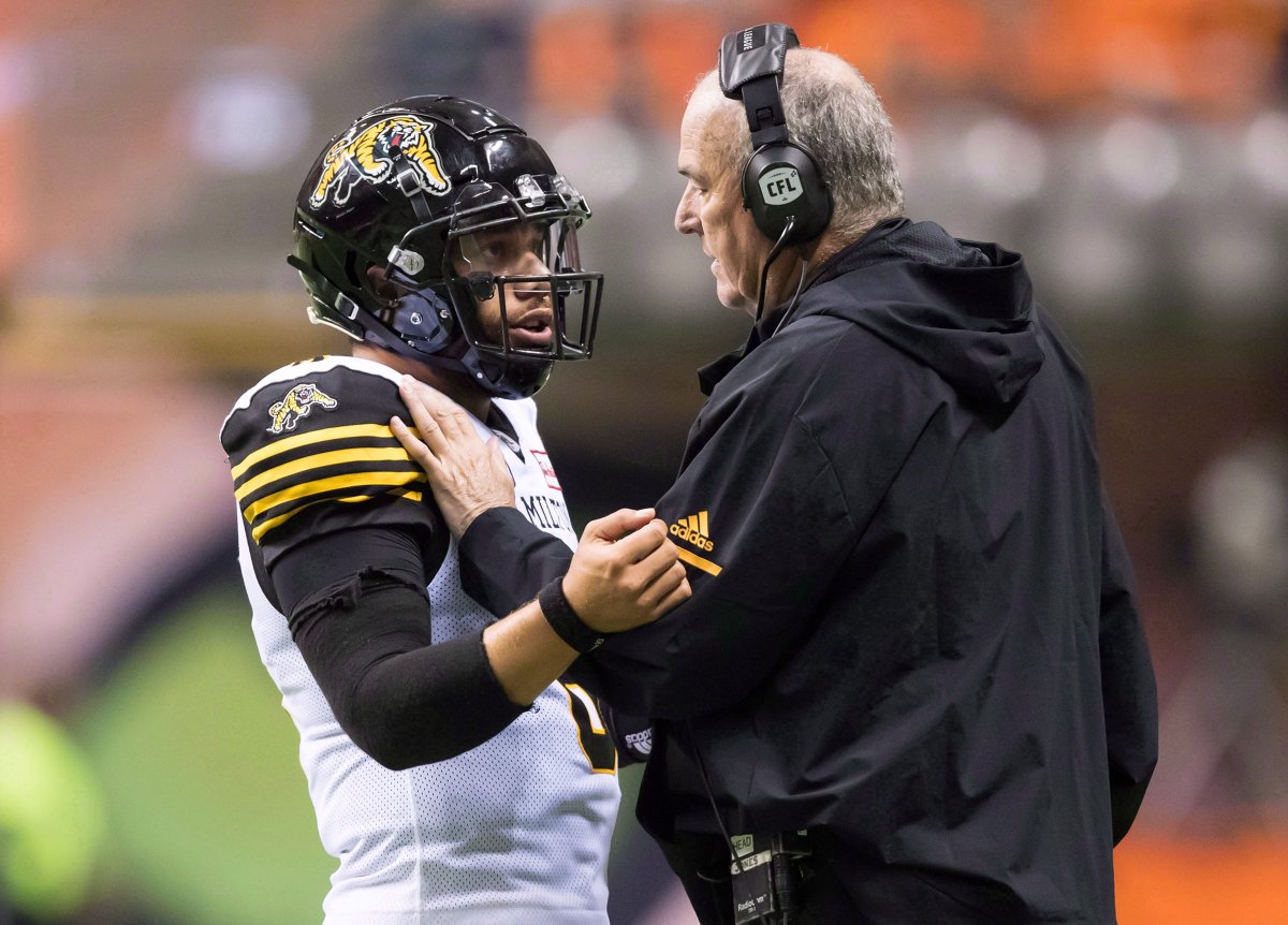Hamilton Tiger-Cats quarterback Jeremiah Masoli, left, listens to head coach June Jones during a break during the second half of a CFL football game against the B.C. Lions, in Vancouver on Saturday, Sept. 22, 2018.