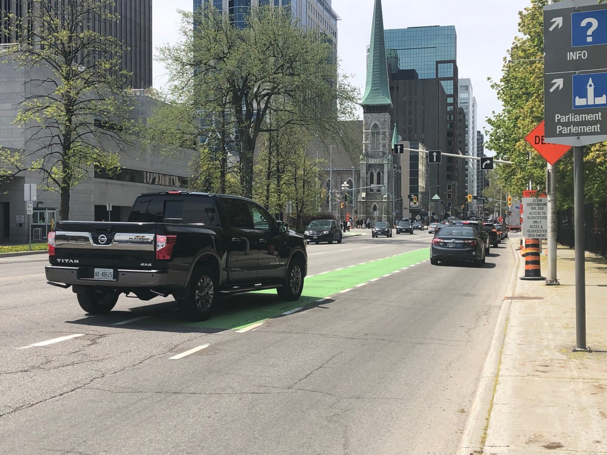 A pick-up truck changes lanes across the floating, westbound bike lane on Laurier Avenue, the same lane where a cyclist was struck on May 16 and later died.