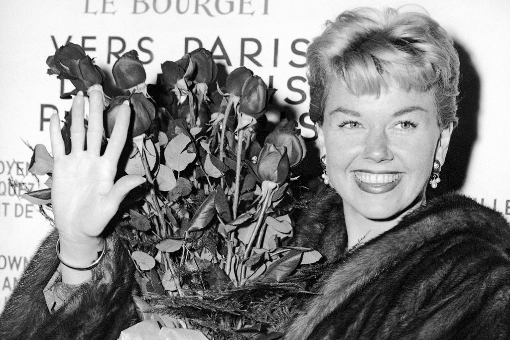 In this April 15, 1955 photo, American actress and singer Doris Day holds a bouquet of roses at Le Bourget Airport in Paris after flying in from London. (AP Photo, File)