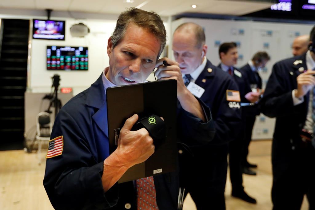 FILE - In this May 1, 2019, file photo, trader Robert Charmak, left, works on the floor of the New York Stock Exchange.