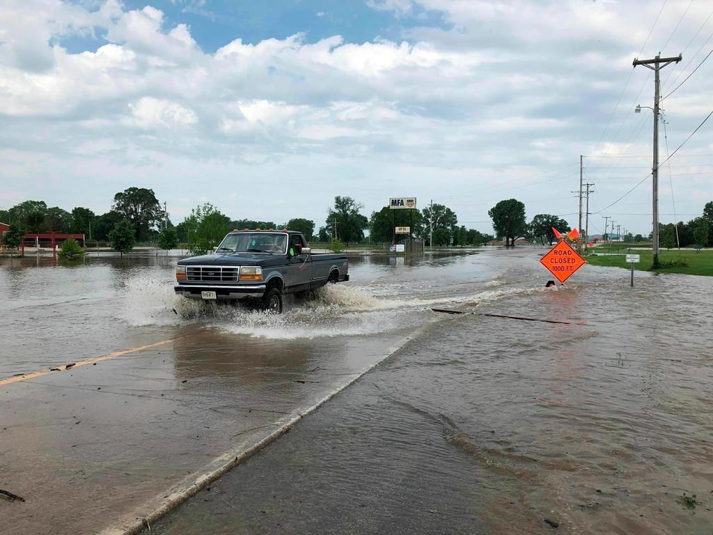 A pickup truck evacuates from an area in north Jefferson City, Mo., as floodwaters from the Missouri River rise over the road on Friday, May 24, 2019.