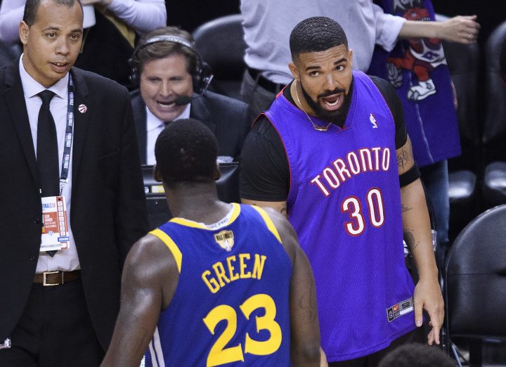 Rapper Drake, right, yells at Golden State Warriors forward Draymond Green (23) after the Toronto Raptors defeated the Warriors in Game 1 of the NBA championship basketball finals in Toronto on Thursday, May 30, 2019.