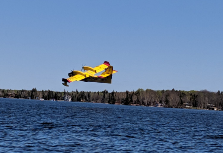 A water bomber flies over Falcon Beach.