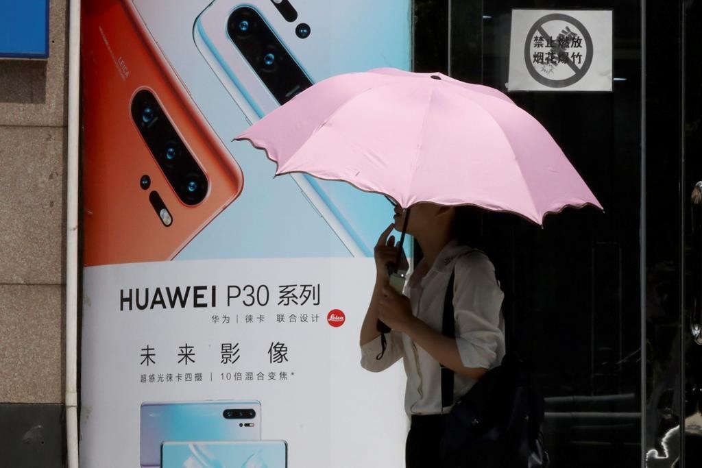 A woman walks past advertisement for Huawei smartphones in Beijing on Thursday, May 16, 2019. In a fateful swipe at telecommunications giant Huawei, the Trump administration issued an executive order Wednesday apparently aimed at banning its equipment from U.S. networks and said it was subjecting the Chinese company to strict export controls.