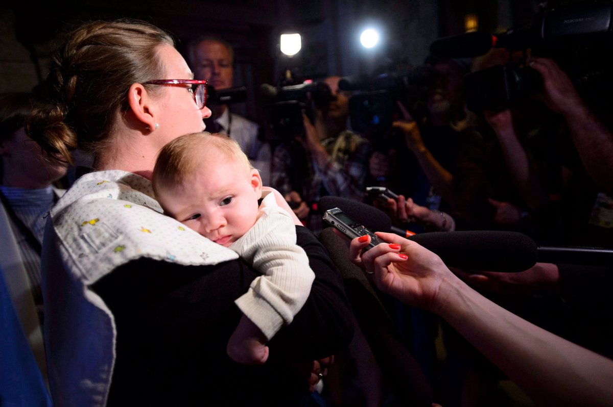 Democratic Institutions Minister Karina Gould pauses to talk to reporters as she carries her three-month-old baby boy Oliver Gerones following a cabinet meeting on Parliament Hill in Ottawa on Tuesday, May 22, 2018. Canada's MPs will soon be eligible to take a 12-month paid parental leave.