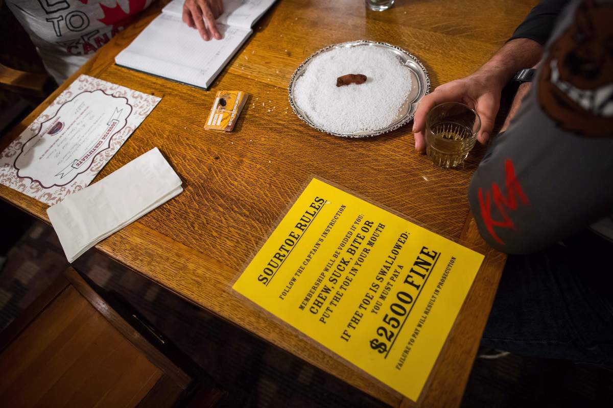 A patron waits to drink the Sourtoe Cocktail, a shot of whisky containing a dehydrated human toe, as the rules are displayed on the table, in Dawson City, Yukon, in a July 1, 2018, file photo.