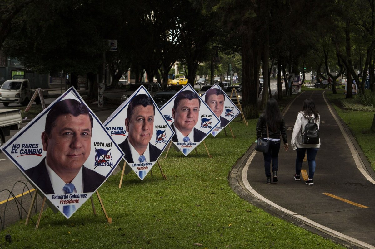 Women walk on the pedestrian path next to campaign posters promoting the ruling party presidential candidate Estuardo Galdamez, in Guatemala City, Saturday, June 15, 2019. The road to Sunday's presidential election in Guatemala has been a chaotic flurry of court rulings and shenanigans, illegal party-switching and allegations of malfeasance that torpedoed the candidacies of two of the top three candidates.