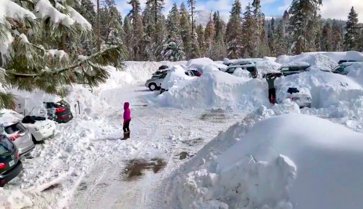 This Wednesday,, Feb. 6, 2019 photo from video by Joel Keeler shows people attempting to clear cars buried in the parking lot of the showed-in Montecito Sequoia Lodge in Kings Canyon National Park in California's Sierra Nevada.