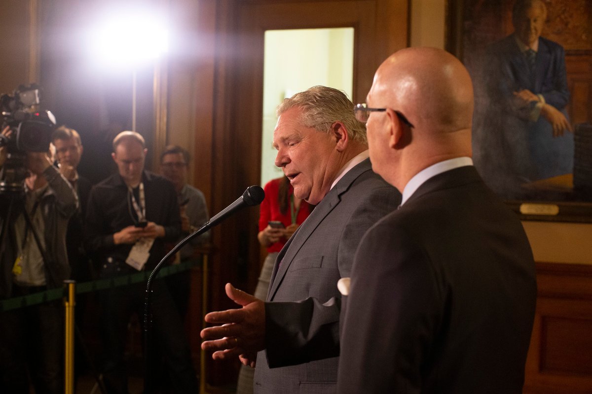 Ontario Premier Doug Ford, left, stands with Steve Clark, Minister of Municipal Affairs and Housing outside his office in the Queen's Park Legislature in Toronto as he takes questions after announcing the cancellation of retroactive cuts that have hit public health, child care and other municipal services, on Monday, May 27, 2019. THE CANADIAN PRESS/Chris Young.