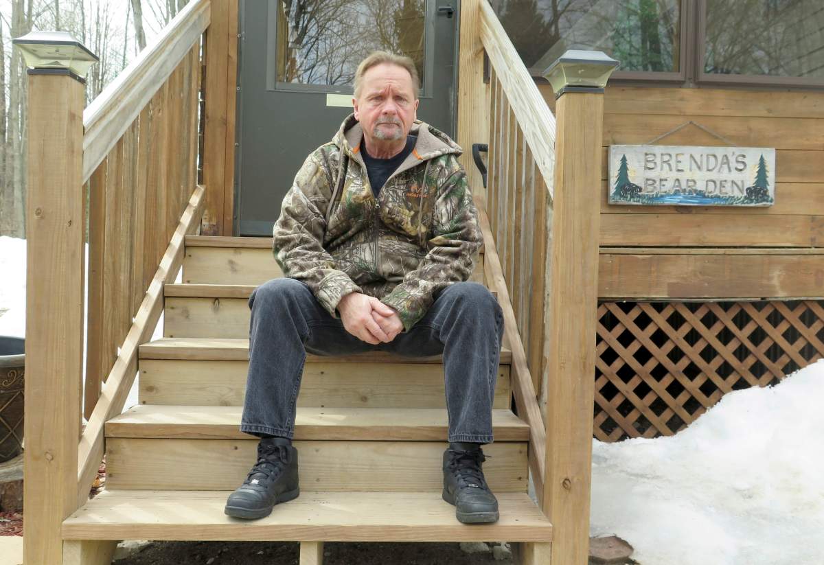 In this April 10, 2019 photo, Wayne Sankey sits on the front steps of his Lakewood, Wis. home where he is the neighbour of Raymand Vannieuwenhoven, who authorities say is the suspect in a cold-blooded 43-year-old cold case murder.