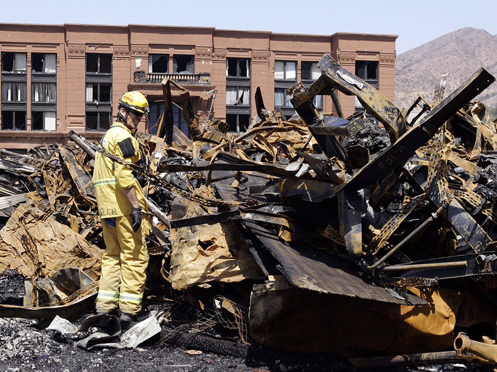 In this June 2, 2008 file photo, Los Angeles County firefighter Darrick Woolever examines metal that needs to be removed at the Universal Studios Hollywood back lot, a day after a fire destroyed the New York Street facade, in the Universal City section of Los Angeles.