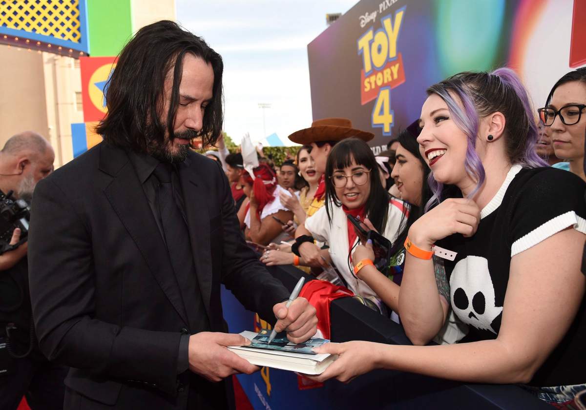 Keanu Reeves signs an autograph as he arrives at the world premiere of ‘Toy Story 4’ on Tuesday, June 11, 2019, at the El Capitan, in Los Angeles, Calif.