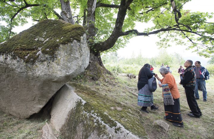 People gather around Lightning Rock following a ceremony of Indigenous leaders in a call to save one of Western Canada’s First Nations burial site in Abbotsford, B.C., Friday, June 14, 2019.