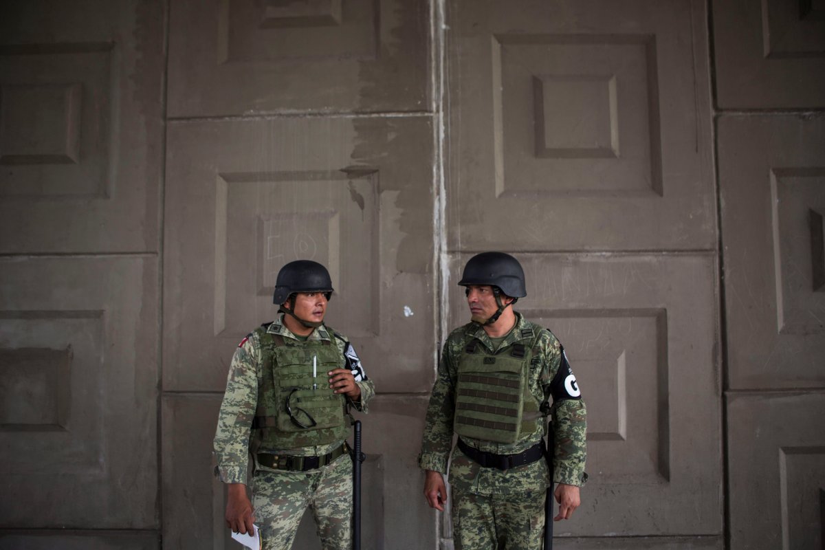 Military police wearing the insignia of the new National Guard provide perimeter security while a migration agent waits to check documents of passengers in passing transport, at an immigration checkpoint in El Manguito, south of Tapachula, Mexico, Friday, June 21, 2019.