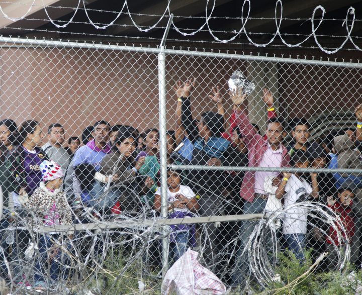 In this March 27, 2019, file photo, Central American migrants wait for food in a pen erected by U.S. Customs and Border Protection to process a surge of migrant families and unaccompanied minors in El Paso, Texas. 