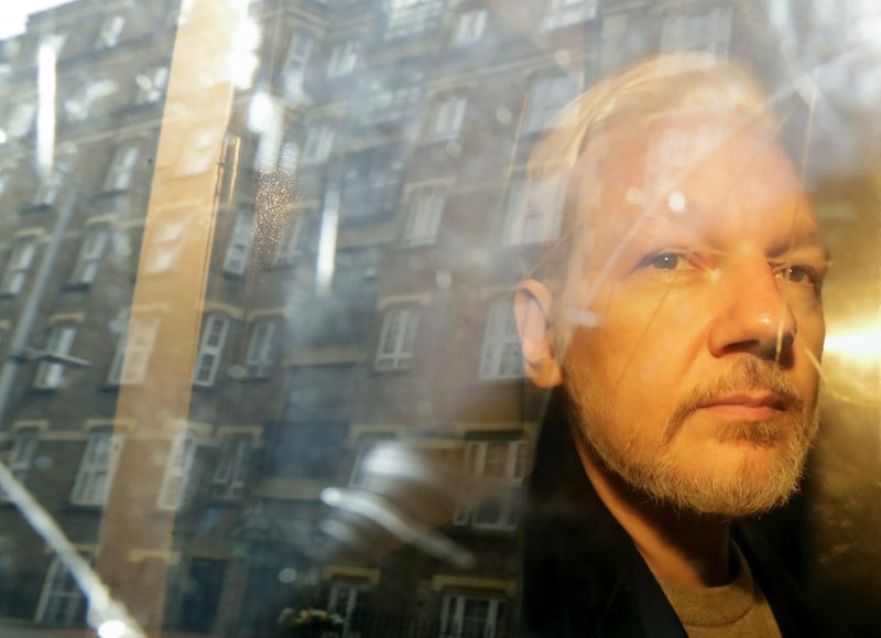 FILE - In this Wednesday, May 1, 2019 file photo, buildings are reflected in the window as WikiLeaks founder Julian Assange is taken from court, where he appeared on charges of jumping British bail seven years ago, in London. 
