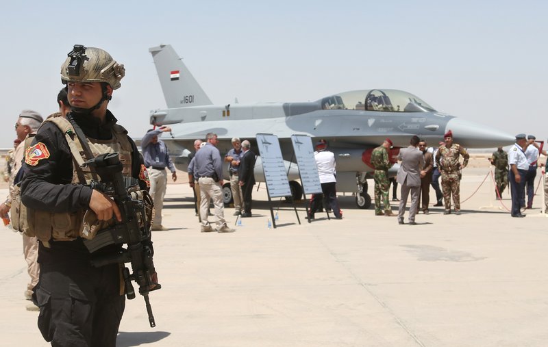 FILE - in this Monday, July 20, 2015 file photo, a member of the Iraqi SWAT team stands guard as security forces and others gather next to a U.S.- made F-16 fighter jet during the delivery ceremony at Balad air base, Iraq.