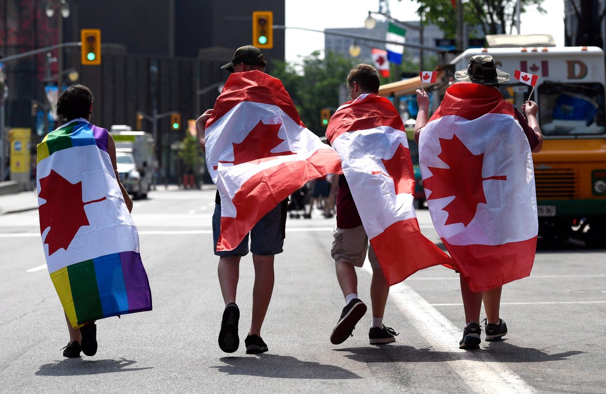 People wear flags as they walk down Elgin Street on Canada Day in Ottawa on Sunday, July 1, 2018.