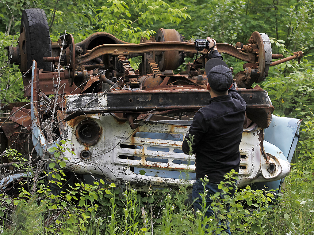 A visitor takes photos of a wrecked car at the Chernobyl exclusion zone in the abandoned city of Pripyat. 