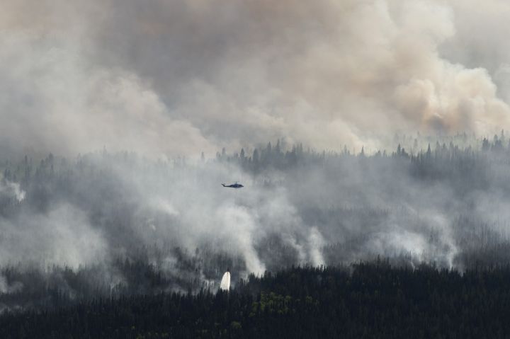 A helicopter drops a bucket of water on the Chuckegg Creek wildfire west of High Level, Alta., in a Saturday, May 25, 2019, handout photo. 