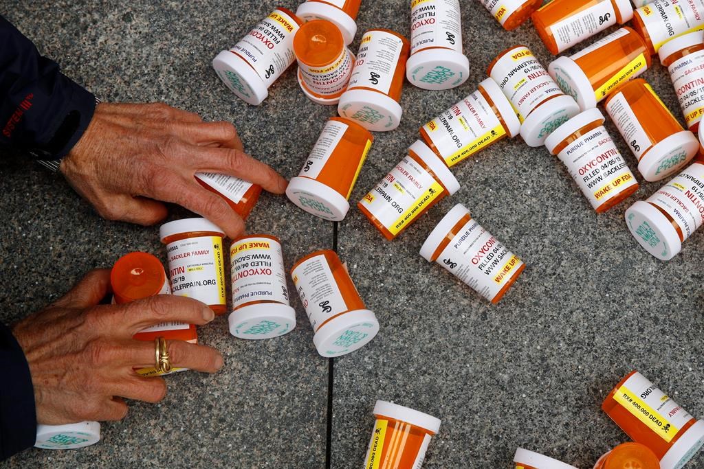 In this Friday, April 5, 2019, file photo, a protester gathers containers at an anti-opioid demonstration in Washington, D.C. Saskatchewan's provincial auditor has tabled a new report that calls for the Ministry of Health to pay closer attention to how highly-addictive opioids are leaving pharmacies. THE CANADIAN PRESS/AP/Patrick Semansky.
