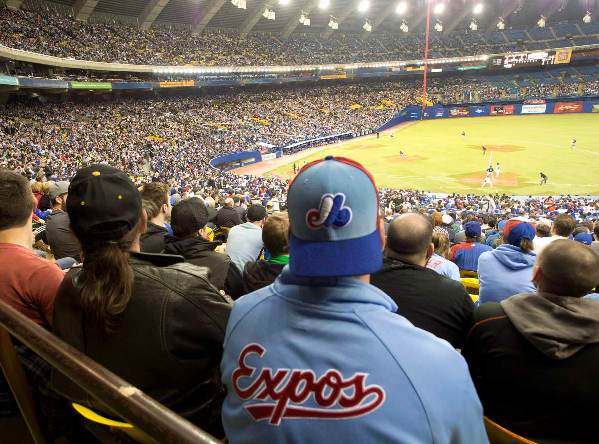 Fans wear Montreal Expos uniforms as they watch the Toronto Blue Jays in a pre-season baseball game against the New York Mets Friday, March 28, 2014 in Montreal.