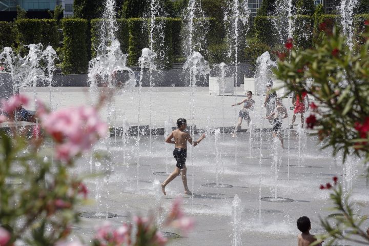 A boy runs in the fountain of Andre Citroen square, in Paris, on Tuesday, June 25, 2019.