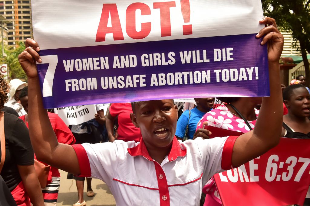 An activist holds up a placard reading 'Act! 7 Women and girls will die from unsafe abortion today' during a demonstration outside the City County Assembly in Nairobi on April 24, 2019.