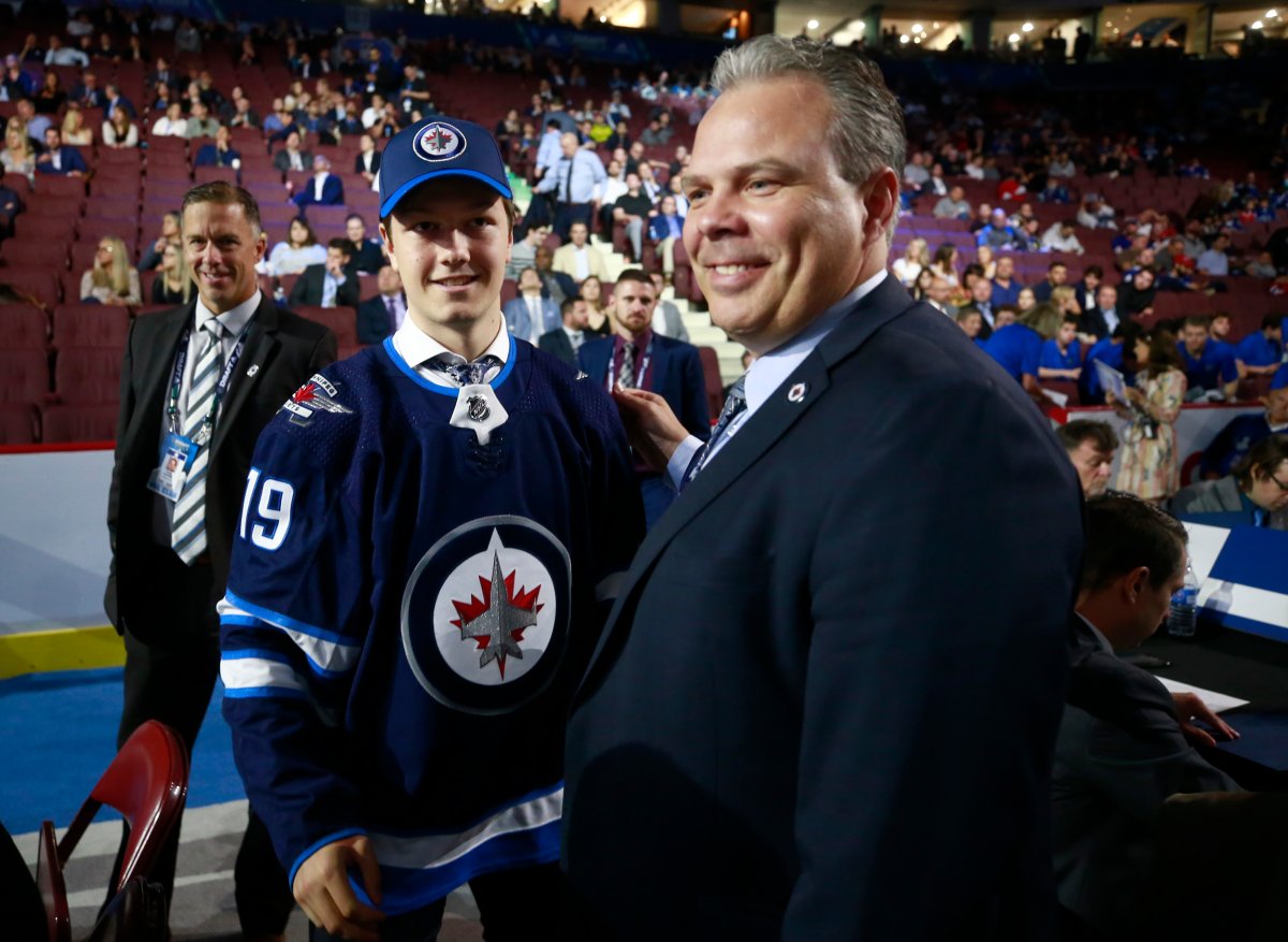 VANCOUVER, BRITISH COLUMBIA - JUNE 22: Simon Lundmark, 51st overall pick of the Winnipeg Jets, is greeted by general manager Kevin Cheveldayoff at the draft table during Rounds 2-7 of the 2019 NHL Draft at Rogers Arena on June 22, 2019 in Vancouver, Canada. (Photo by Jeff Vinnick/NHLI via Getty Images).