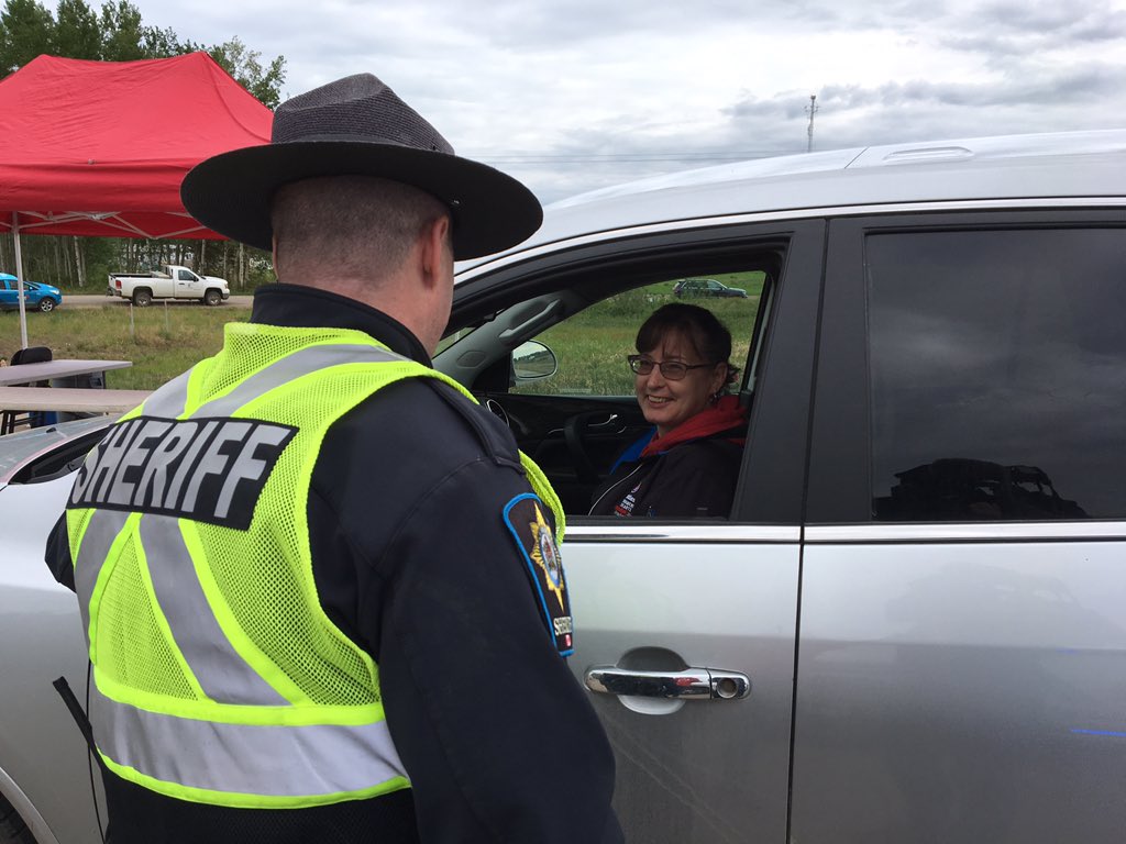 File photo of an Alberta Sheriff greeting a returning resident in High Level, Alta. on Monday, June 3, 2019, two weeks after the community was evacuated due to a wildfire near the northern Alberta town.