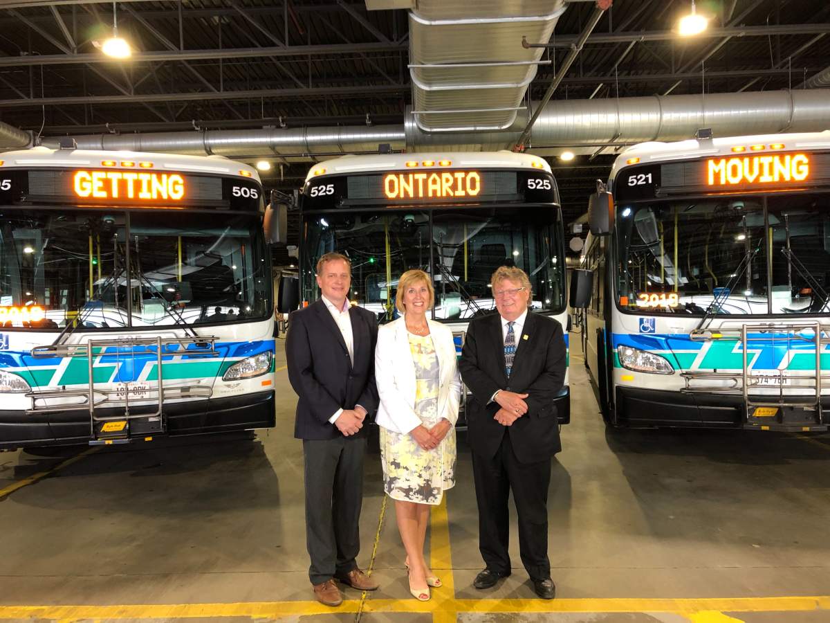 Environment Minister Jeff Yurek, left, stands with Transportation Minister Laurie Scott, middle, and London Mayor Ed Holder inside a bus barn at the London Transit Commission's Highbury Avenue headquarters.