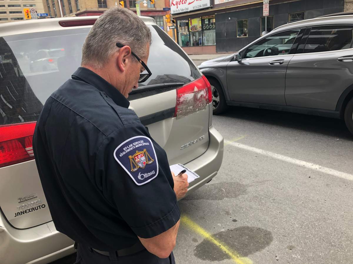 Parking control officer Danis Lafrance issues a ticket to a vehicle parked in a "no-stopping zone" during Monday's afternoon rush-hour period in downtown Ottawa. The City of Ottawa has got extra bylaw and police officers monitoring streets and intersections for the next two weeks in an effort to ease gridlock on busy roads.
