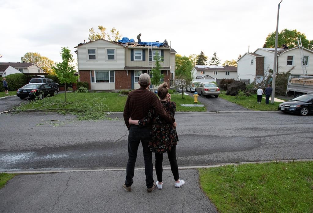 Dominik Lesniewski and Catherine O'Sullivan look at damage to their roof caused by a tornado in the Ottawa suburb of Orleans, on June 2, 2019.