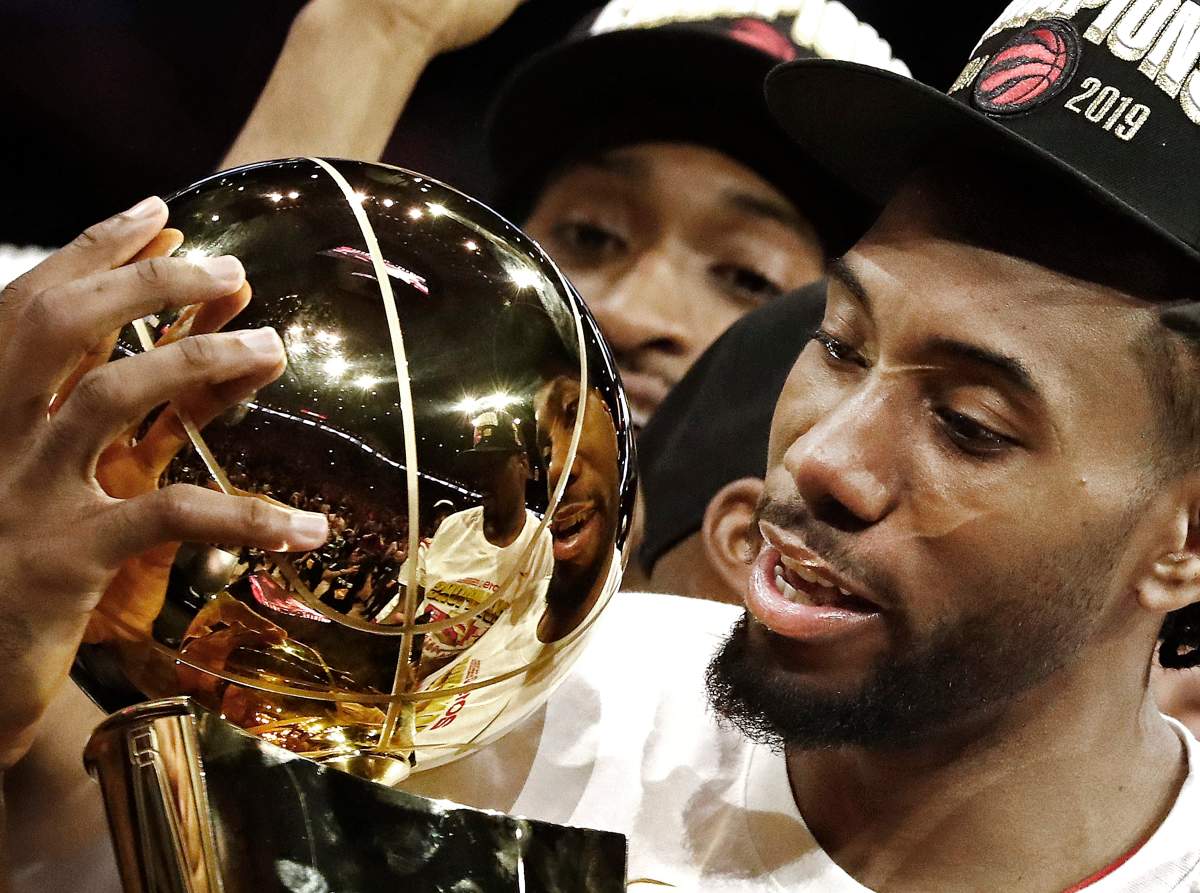 Toronto Raptors forward Kawhi Leonard (C) holds up the Larry O'Brien NBA Championship Trophy after beating the Golden State Warriors in the NBA Finals game six at Oracle Arena, in Oakland, California, 13 June 2019.