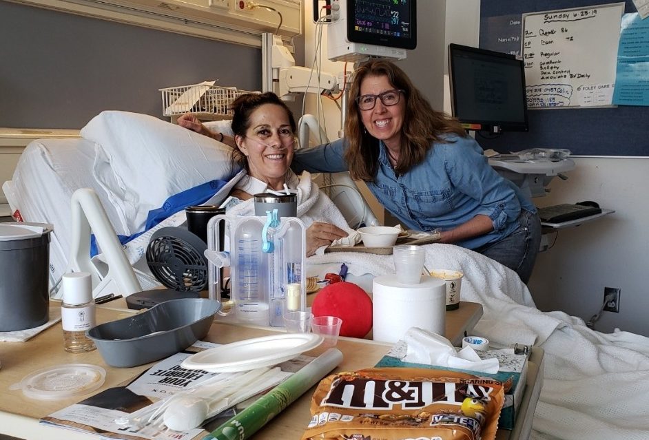 Lynn Phillips sits in her hospital bed at Ronald Reagan UCLA Medical Center in Los Angeles while a friend visits her on Monday, June 24, 2019. Phillips was run over twice by the same driver while in Santa Monica on June 13, suffering extensive injuries.