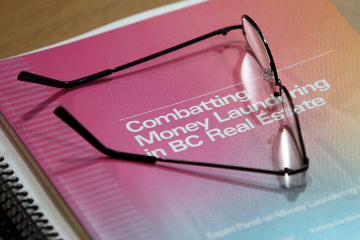 Glasses rest on a copy of Peter German’s investigation report into money laundering in the B.C. real estate industry during a press conference in Victoria, B.C., on Thursday, May 9, 2019.