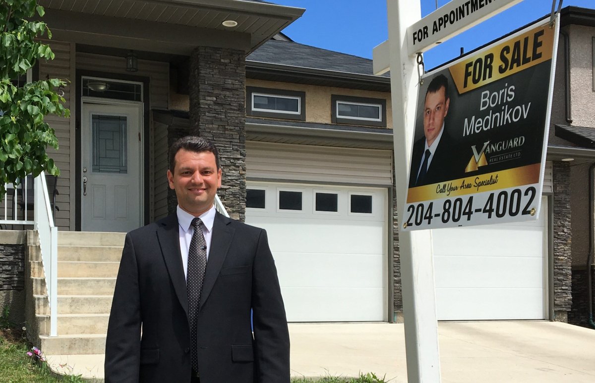 Real estate agent Boris Mednikov poses outside a home in Winnipeg's Bridgewater neighbourhood.