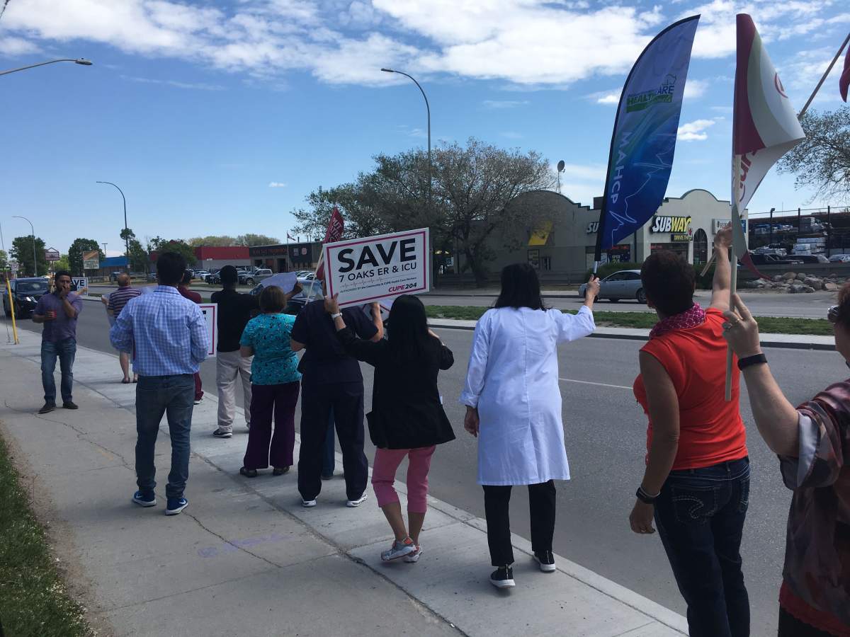 Supporters wave flags and hold signs, receiving encouraging honks from drivers coming down McPhillips.