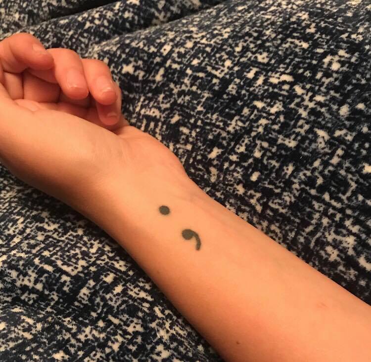 The semicolon tattoo is a symbol of solidarity and support in the mental health community.