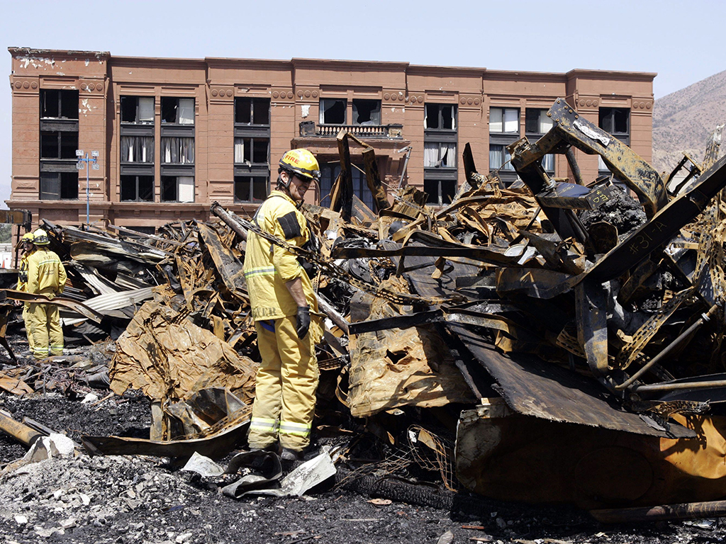 In this June 2, 2008, file photo, Los Angeles County firefighter Darrick Woolever examines metal that needs to be removed at the Universal Studios Hollywood backlot, a day after a fire destroyed the New York Street facade, in the Universal City section of Los Angeles.