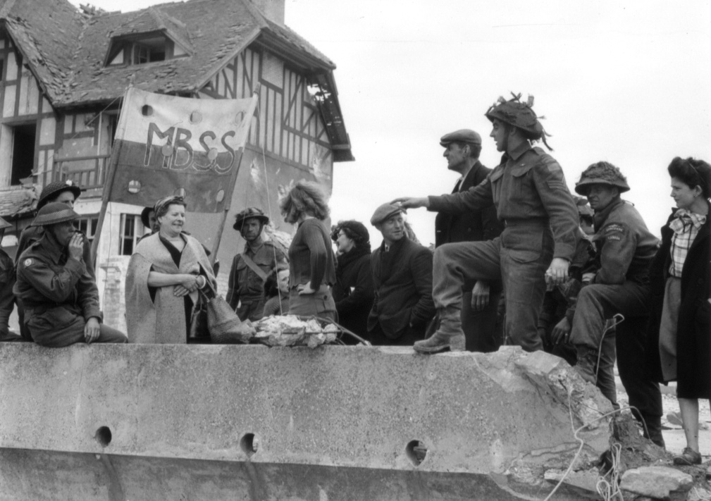 Canadian infantrymen from Le Régiment de la Chaudière talking with French civilians in Bernières-sur-Mer, France, on 6 June 1944.