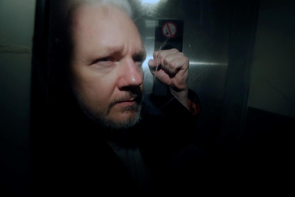 In this May 1, 2019, file photo, WikiLeaks founder Julian Assange puts his fist up as he is taken from court in London. The Justice Department has charged Assange with receiving and publishing classified information.