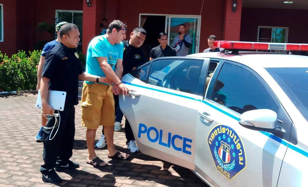 In this June 15, 2019 photo released by Crime Suppression Division, Italian Francesco Galdeli, centre, is detained by Thai police officers at a house in Chonburi. (Crime Suppression Division of Thailand via AP)