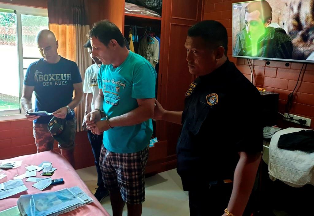 In this June 15, 2019, photo released by Crime Suppression Division, Italian Francesco Galdeli, centre, is arrested by Thai police officers at a house in Chonburi.  (Crime Suppression Division of Thailand via AP)